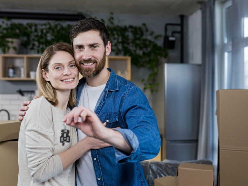 pareja sonriente sujetando las llaves de su nuevo hogar